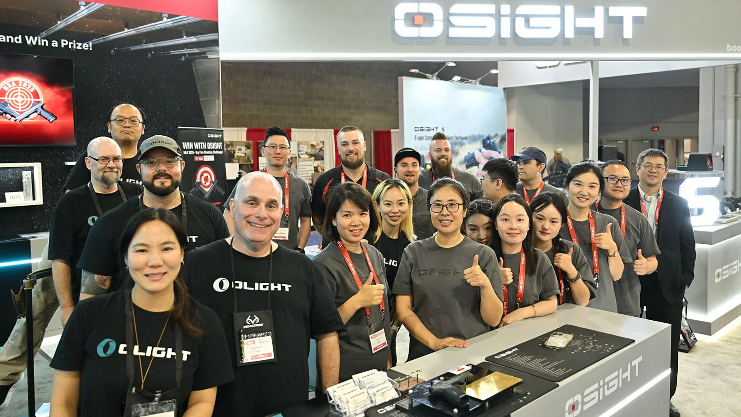 Group of people smiling and posing at a trade show booth with Osight branding in the background.